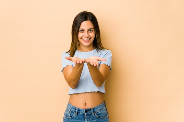 Mujer joven en pared beige sosteniendo algo con palmeras