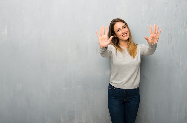 Mujer joven en la pared con textura contando diez con los dedos