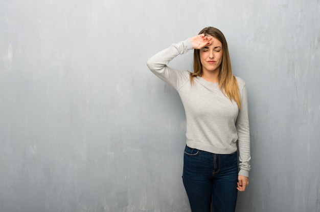 Mujer joven en la pared con textura con expresión cansada y enferma