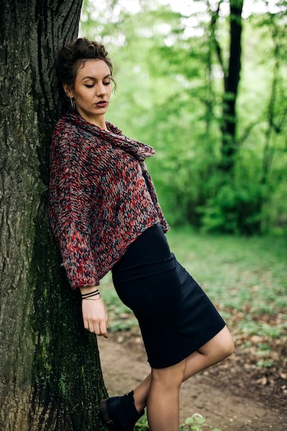 Mujer joven en el parque por el árbol