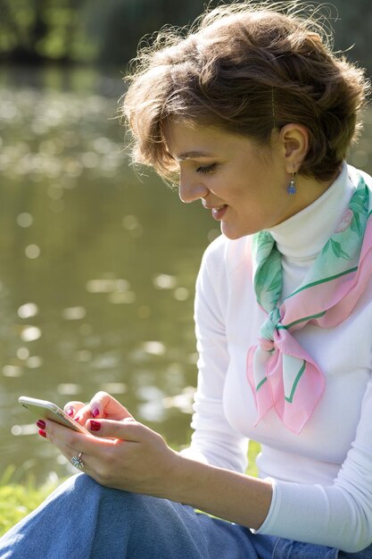 Mujer joven en el parque habla por teléfono móvil Retrato de niña linda en estilo francés