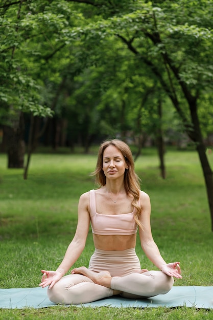 Mujer joven en el parque en el verano a yoga y meditación