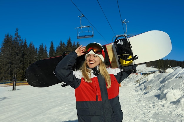 Mujer joven con pasamontañas con snowboard al aire libre