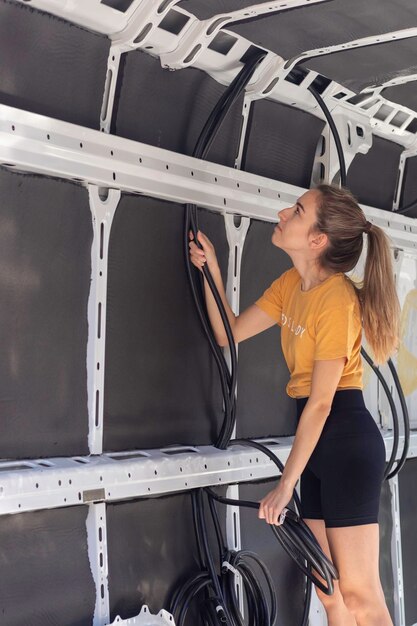 Mujer joven pasando por el cableado eléctrico para la instalación eléctrica de la autoconstruida