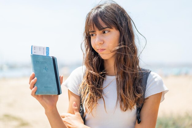 Mujer joven con pasaporte al aire libre con expresión triste