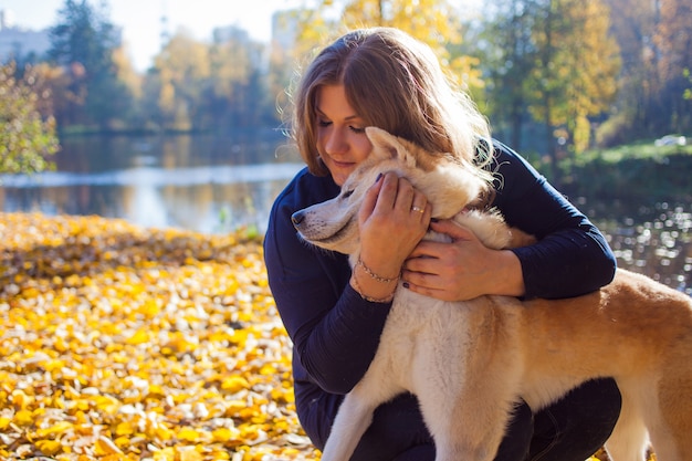 Mujer joven en un paseo con su perro de raza Akita inu