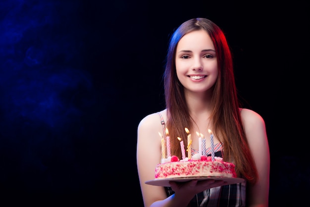 Mujer joven con pastel de cumpleaños en la fiesta