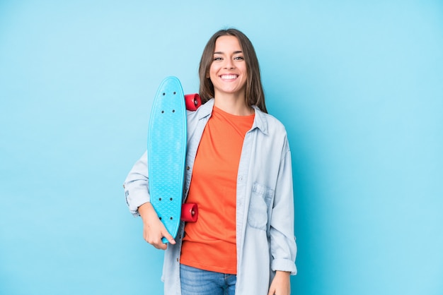 Mujer joven patinadora caucásica en pared azul