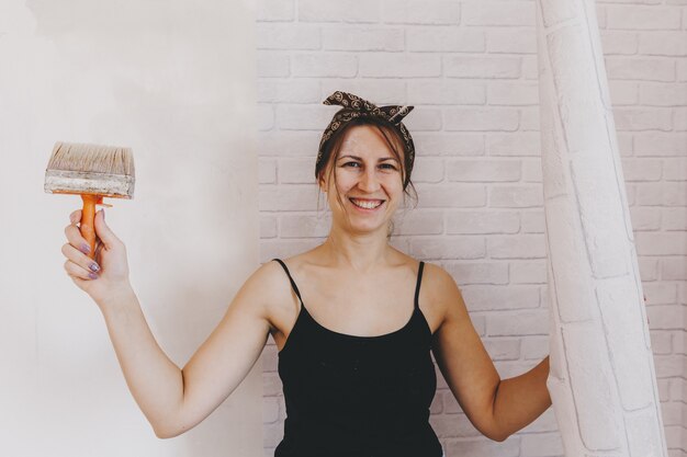 Mujer joven pega papel tapiz en casa. chica pega papel tapiz en forma de ladrillo. reparar.