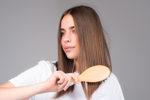 Mujer joven peinando el cabello sano y brillante aislado en estudio