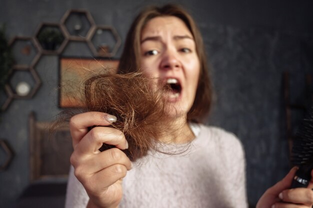 Mujer joven en peine con pelo, horror y rabieta, problemas de cabello