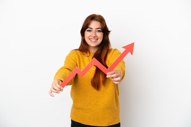 Foto mujer joven pelirroja aislada sobre fondo blanco sosteniendo una captura de una flecha ascendente con expresión feliz