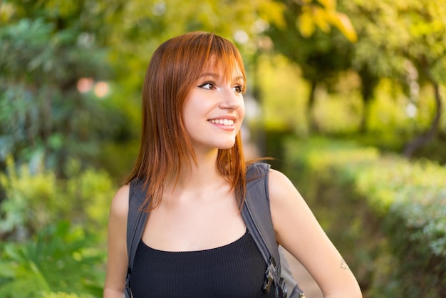 Mujer joven pelirroja bonita al aire libre con expresión feliz