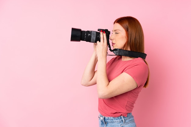 Mujer joven pelirroja con una cámara profesional