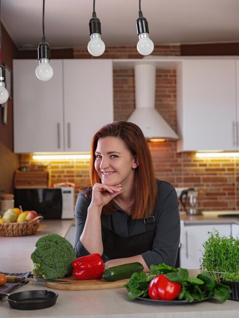 Mujer joven pelirroja cocinando en la cocina Comer sano en casa