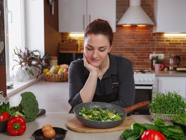 Mujer joven pelirroja cocinando en la cocina Comer sano en casa