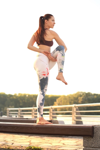 Mujer joven pelirroja deportes hacer ejercicio de yoga de estiramiento al aire libre.