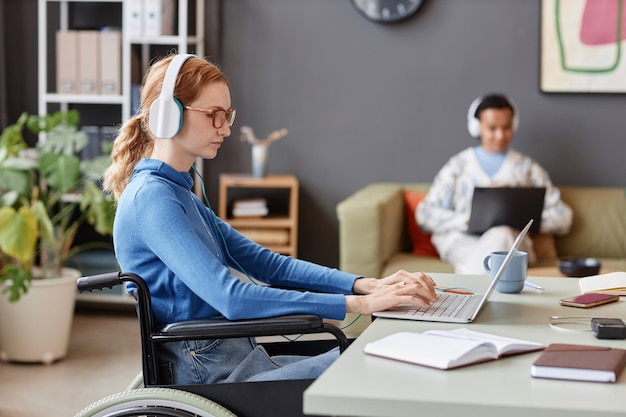 Mujer joven pelirroja con discapacidad usando computadora trabajando en su empresa