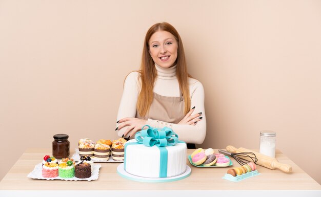 Mujer joven pelirroja con un gran pastel riendo