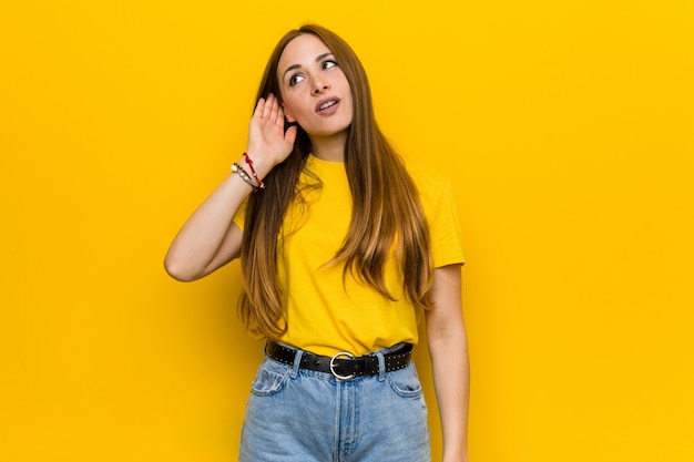 Mujer joven pelirroja jengibre tratando de escuchar un chisme.