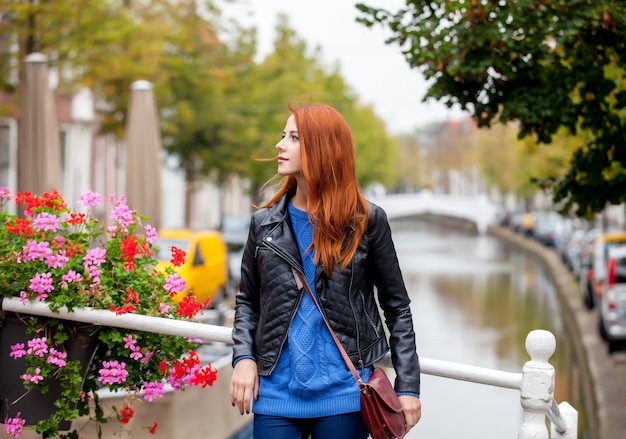 Mujer joven pelirroja de pie en la calle en la ciudad de Amsterdam en primavera.