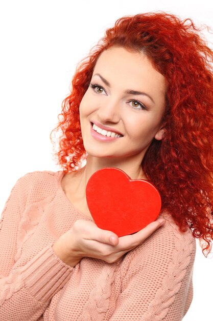 Mujer joven pelirroja sosteniendo corazón, aislado en blanco