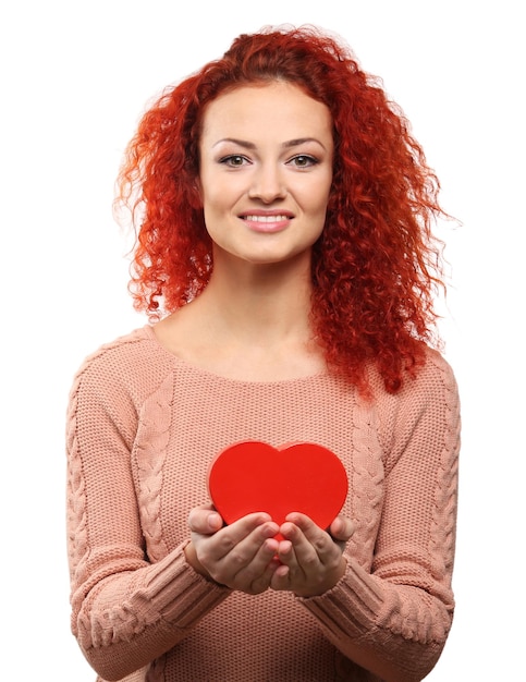 Mujer joven pelirroja sosteniendo corazón aislado en blanco