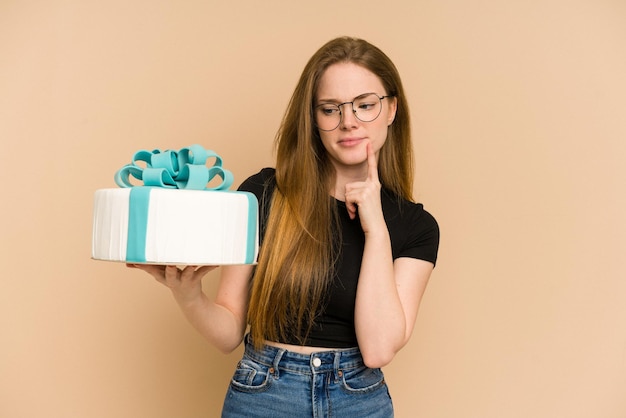 Mujer joven pelirroja sosteniendo un pastel dulce cortado aislado