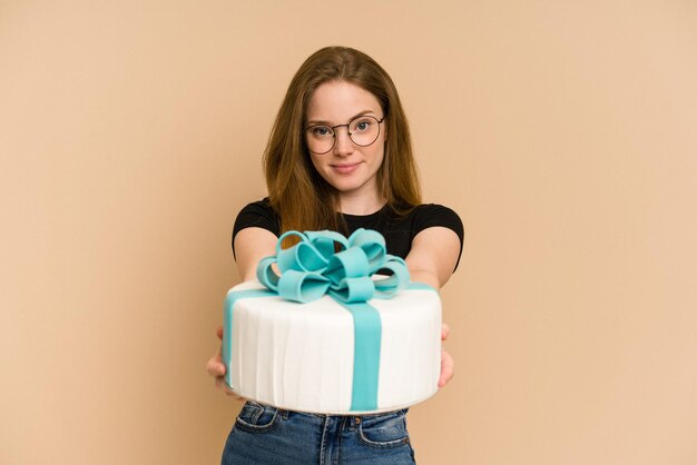 Mujer joven pelirroja sosteniendo un pastel dulce cortado aislado