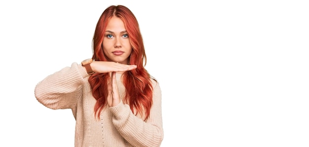 Foto mujer joven pelirroja con suéter de invierno casual haciendo gesto de tiempo fuera con las manos frustradas y cara seria