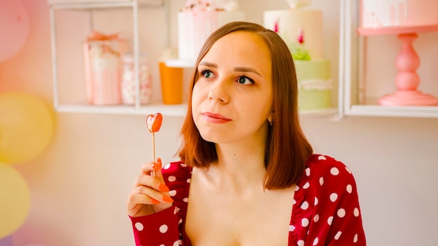 mujer joven, con, pelo corto, lamer, piruleta, retrato, de, dama positiva, en, vestido rojo, con, caramelo