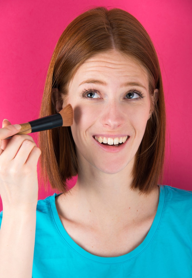 Foto mujer joven de pelo de jengibre con pincel de maquillaje