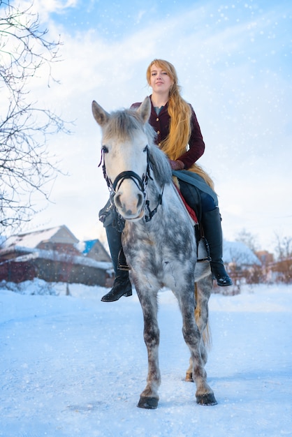 Mujer joven con pelo largo con caballo en invierno