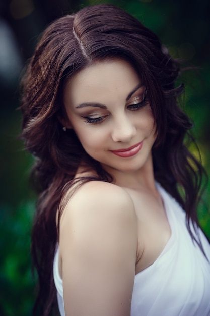 Mujer joven con pelo largo y cara bonita en vestido blanco posando