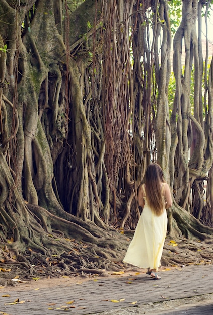 Mujer joven de pelo largo cerca de un árbol de higuera