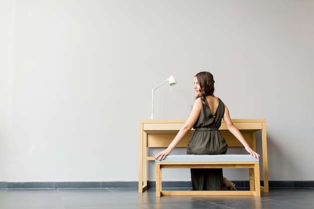 Mujer joven de pelo largo sentado junto a la mesa en la habitación