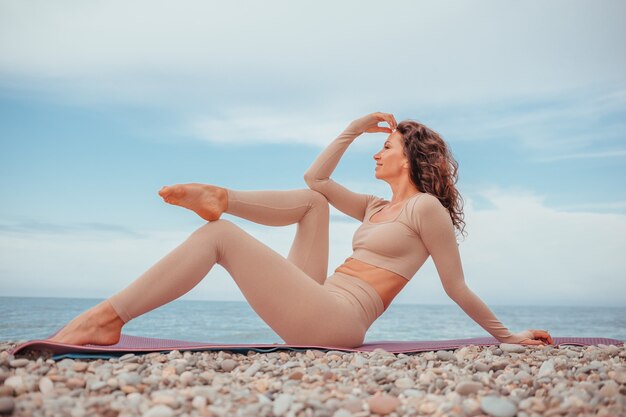 Mujer joven con pelo negro instructor de fitness en leggings y tops haciendo estiramientos y pilates en