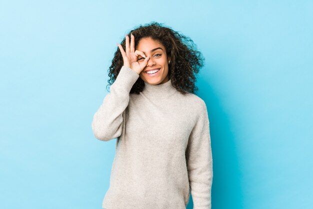 La mujer joven del pelo rizado del afroamericano excitó guardar gesto aceptable en ojo.