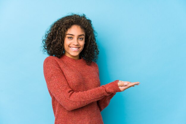 Mujer joven del pelo rizado del afroamericano que lleva a cabo un espacio de la copia en una palma.