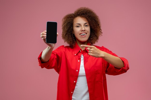 Mujer joven de pelo rizado con un teléfono inteligente en las manos