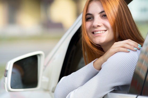 Mujer joven con el pelo rojo conduciendo un coche.