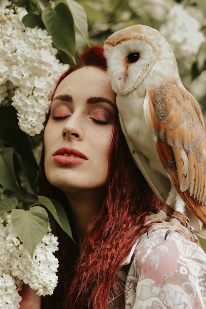 mujer joven, con, pelo rojo, en, un, lila, jardín, con, un, búho, lechuza común