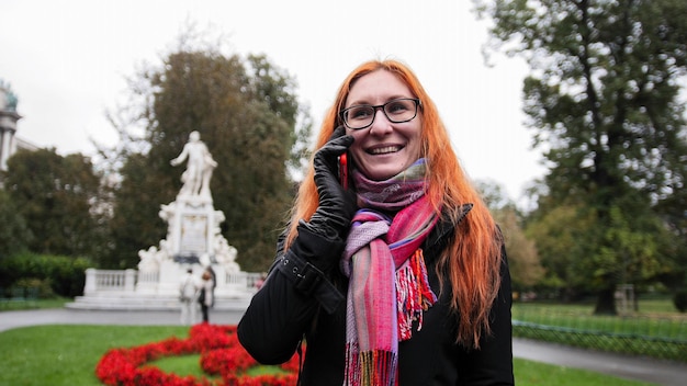 Mujer joven de pelo rojo con teléfono celular en Viena, gran angular