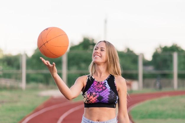 Mujer joven con una pelota de baloncesto en una cancha de baloncesto al aire libre