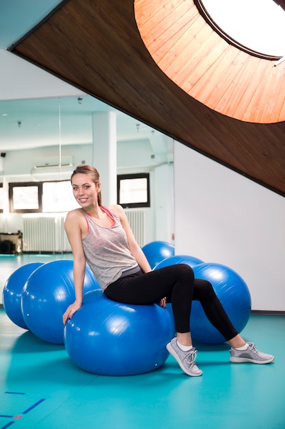 Mujer joven en pelota de pilates en el gimnasio