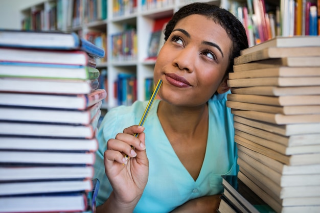 Mujer joven pensativa en biblioteca