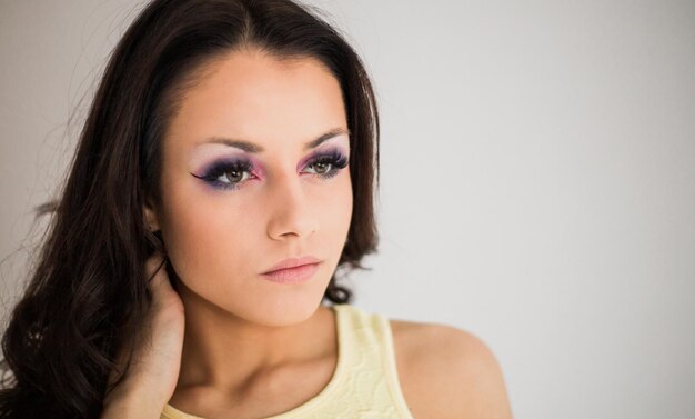 Foto mujer joven pensativa con el cabello largo contra un fondo blanco