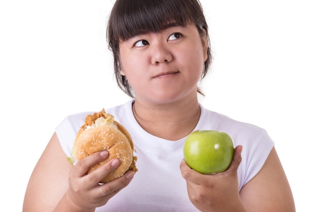Foto mujer joven pensativa sosteniendo una hamburguesa y una manzana de abuela smith contra un fondo blanco