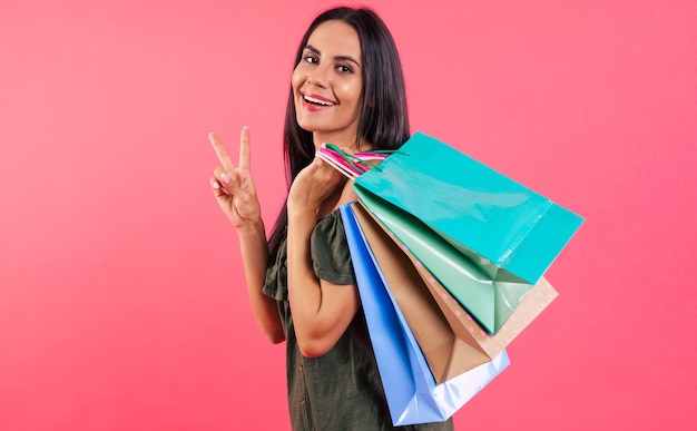 Mujer joven perfecta con un traje casual sostiene una pila de bolsas de papel de compras