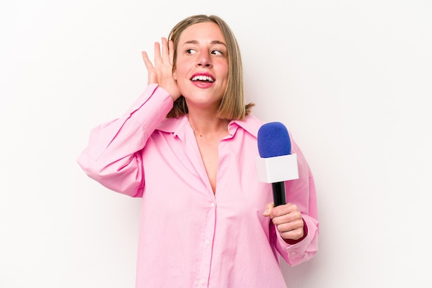 Mujer joven periodista caucásica aislada de fondo blanco tratando de escuchar un chisme